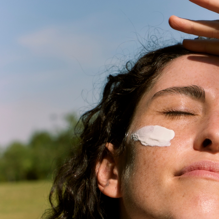 Ragazza si copre dai raggi solari, ha la protezione solare sul viso