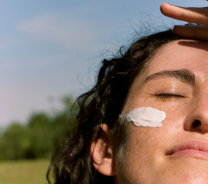 Ragazza si copre dai raggi solari, ha la protezione solare sul viso